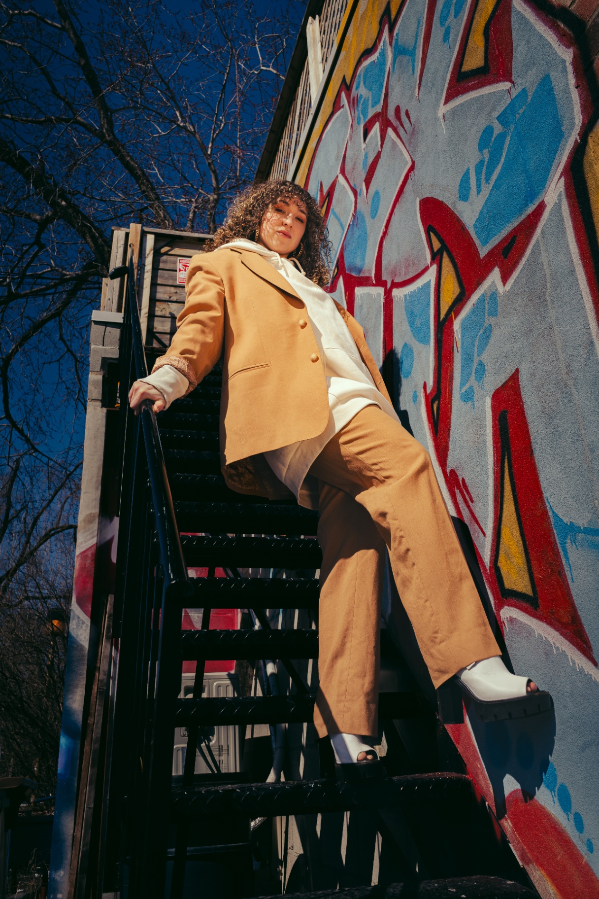 Community member on a fire escape with a graffiti wall in the background.